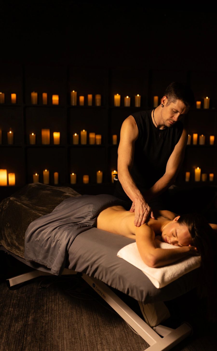 Massage student working in a candlelit treatment room at Spa One in Layton, Utah