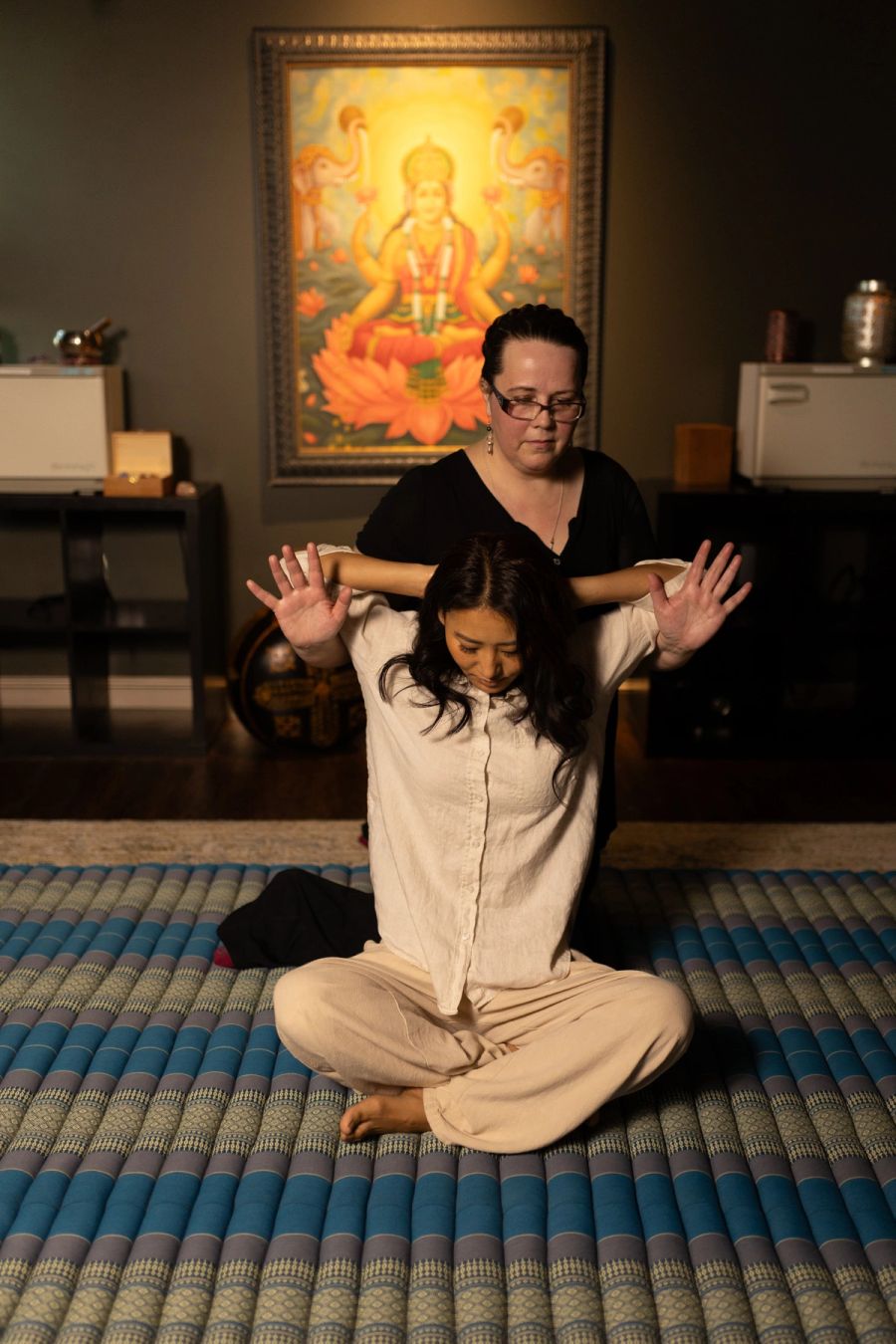 Instructor demonstrating Thai massage stretching while students watch