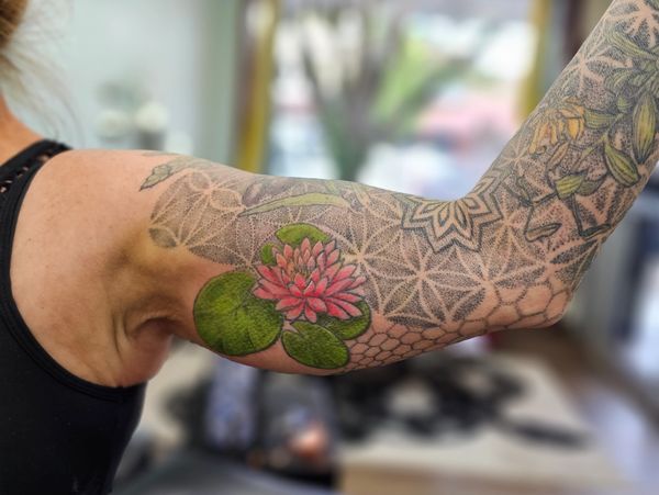 full sleeve with focus on fresh color added to lotus on inner bicep, shop in background
