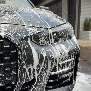Close-up of a car covered in soap suds during a wash.