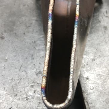 Close-up of a metal piece with detailed welding on its edge.