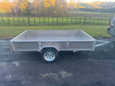 Small aluminum utility trailer hitched to a vehicle.