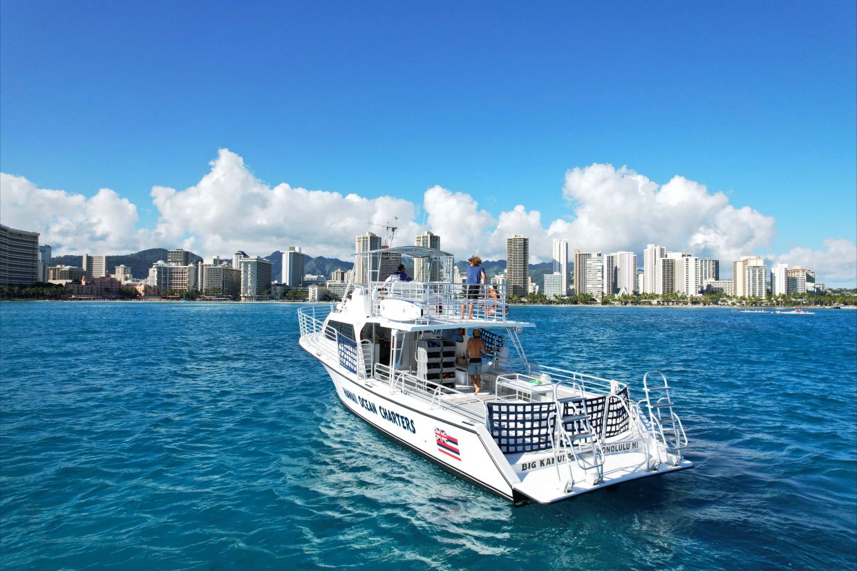 Charter boat on blue ocean near city skyline.