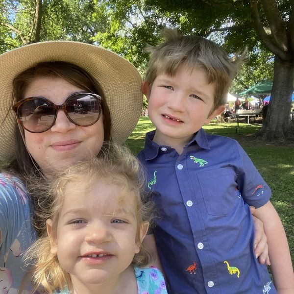 A woman with two children outdoors on a sunny day.