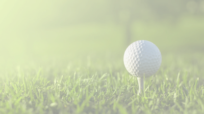 Golf ball on a tee with green grass background.