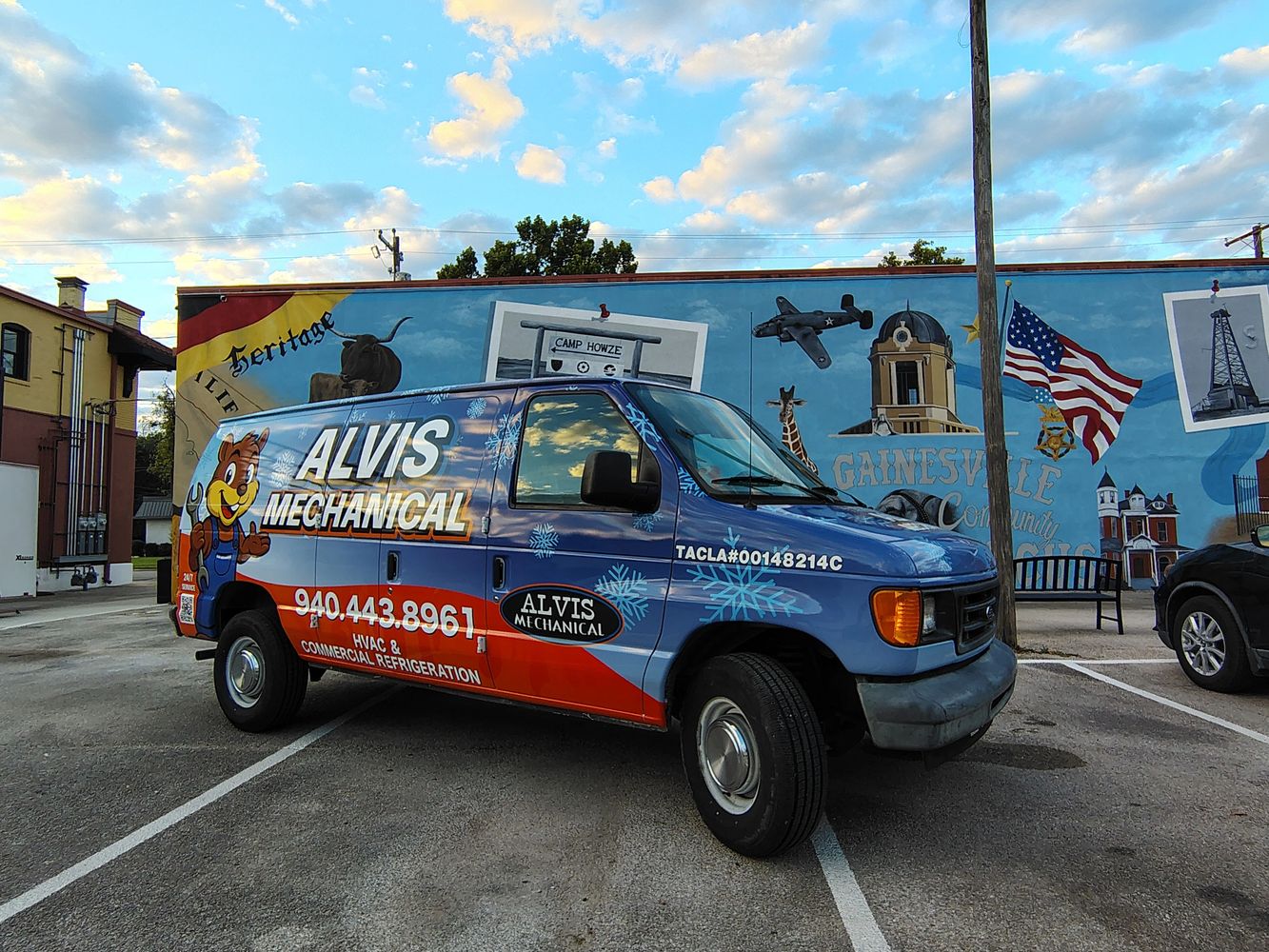 Blue and red Alvis Mechanical van parked in front of a colorful mural.