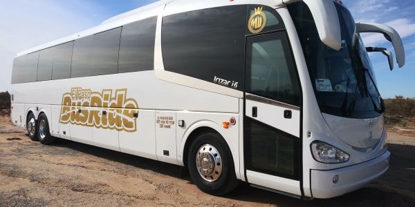 White El Paso BusRide passenger bus parked on dirt road under blue sky.