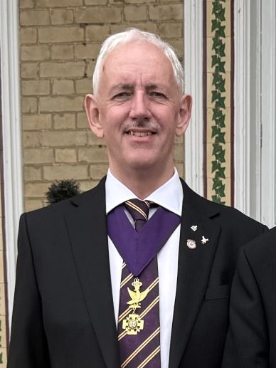 Man in formal suit with medal and tie.