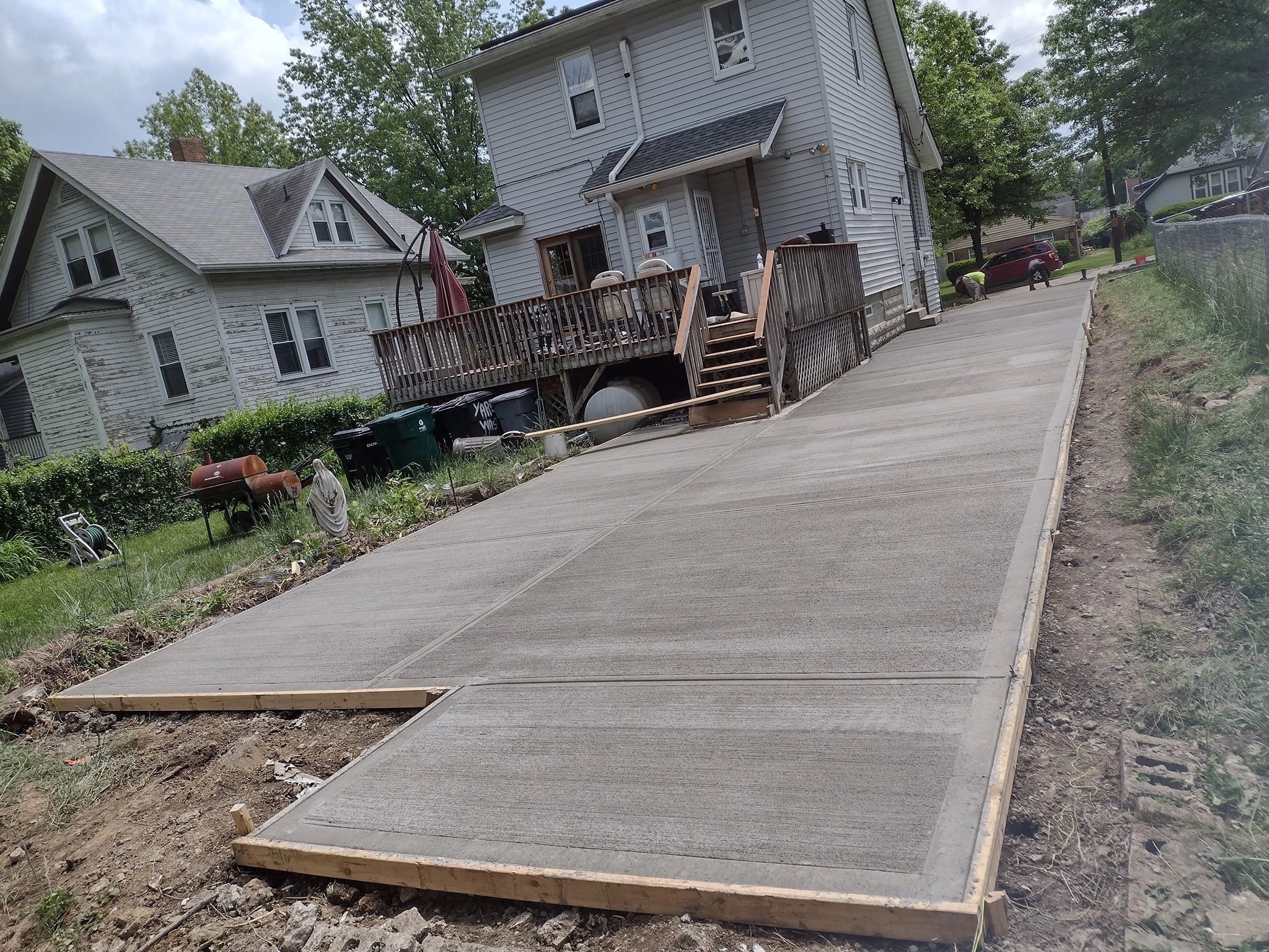 Newly poured concrete driveway beside homes.