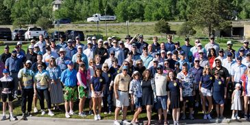 Large group photo of people on a golf course on a sunny day.