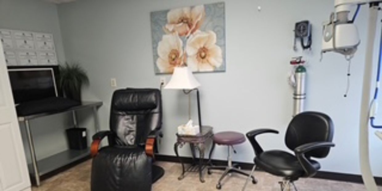 A cozy medical examination room with black chairs and floral wall art.