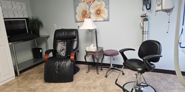 A cozy medical examination room with black chairs and floral wall art.