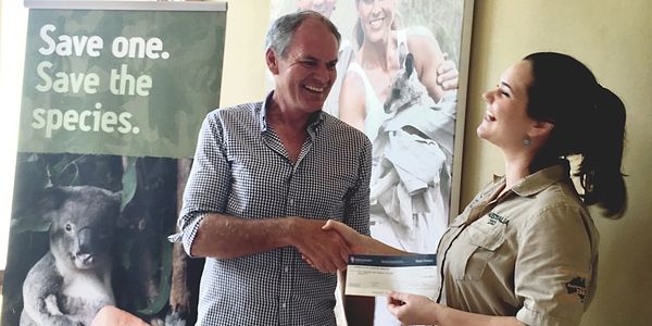 Two people exchanging a check with a nature conservation banner.
