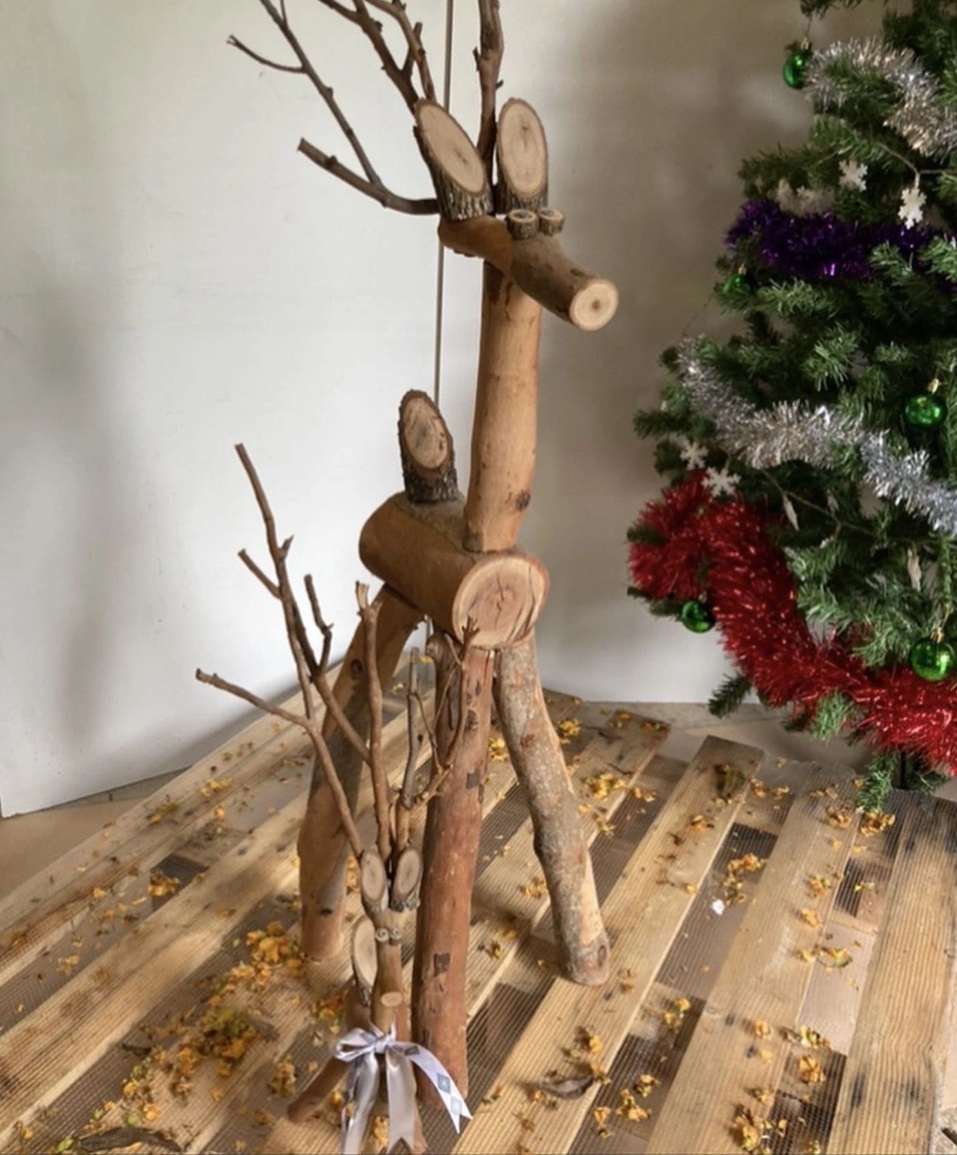Wooden reindeer sculptures next to a decorated Christmas tree.