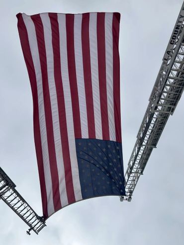 American flag hanging upside down between two ladders.