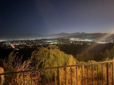 Cityscape at night with lights and mountains.