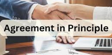 Two people shaking hands over a desk with documents and a laptop.