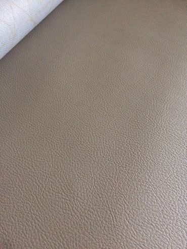 Close-up of textured beige leather surface with a roll of white fabric in the corner.