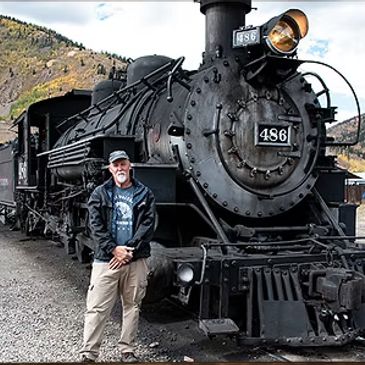 Man standing next to a vintage black steam locomotive numbered 486.
