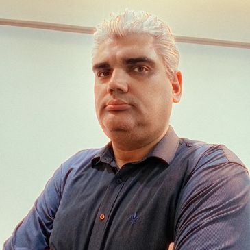 Man with white hair posing confidently indoors.