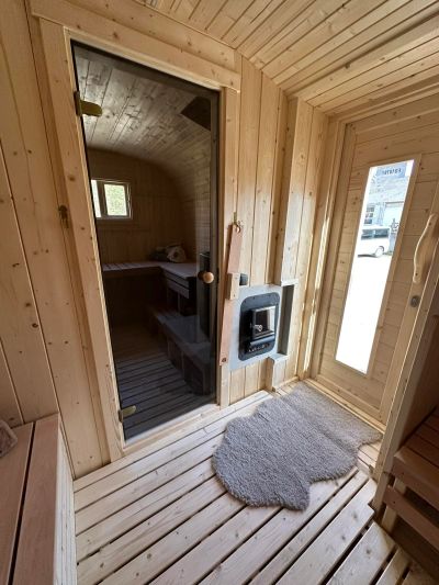 Interior view of a wooden sauna with glass door and cozy seating inside.