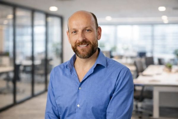 Smiling man in blue shirt in a modern office setting.