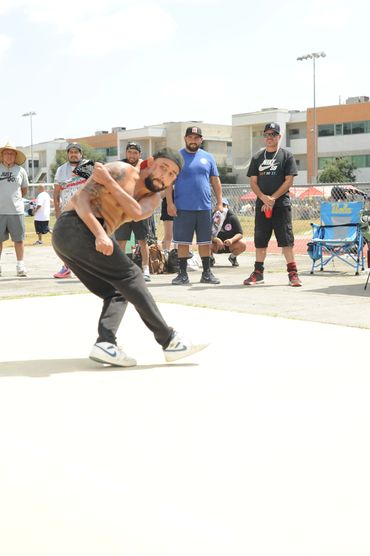 Man breakdancing outdoors with people watching.