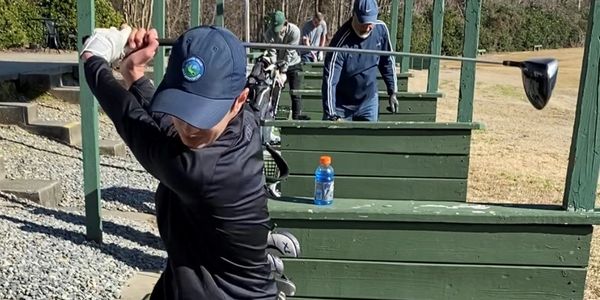 Junior golfer backswing on driving range.