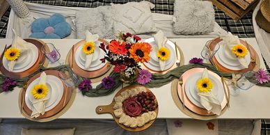 An indoor picnic tablescape decorated with flowers and floor pillows.