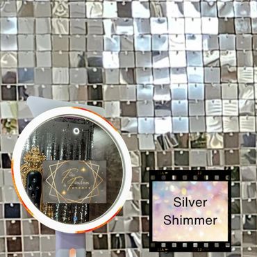 A selfie ring light mirror photo booth in front of a silver shimmer wall backdrop.