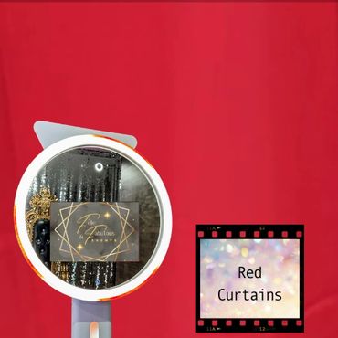 A selfie ring light mirror photo booth in front of a red curtain backdrop.