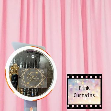 A selfie ring light mirror photo booth in front of a pink curtain backdrop.