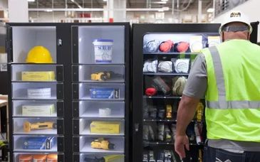 Worker accessing safety gear from organized storage lockers in a warehouse.