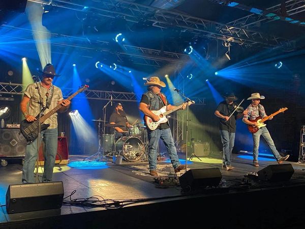 Country band performing live on stage with vibrant lighting.