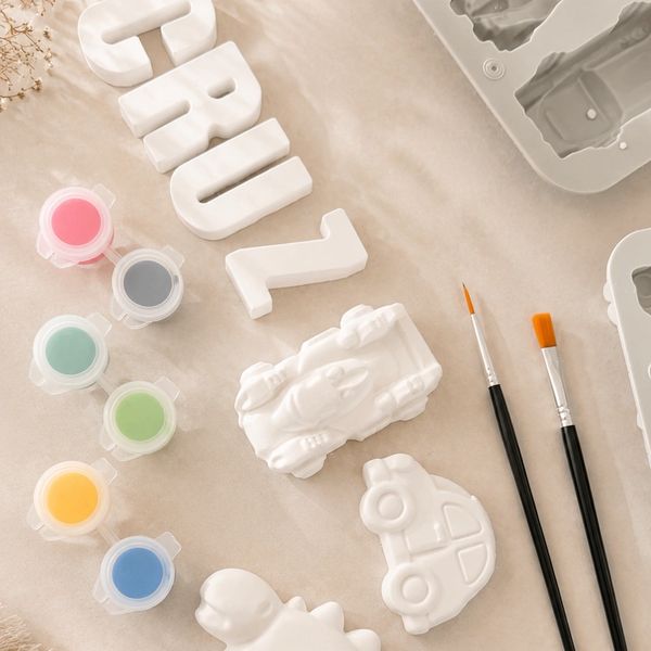 Crafting supplies with molds, paints, and brushes.
