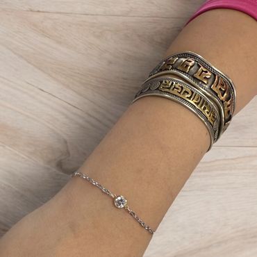 Close-up of a dainty permanent bracelet featuring a bezel-set gemstone. 