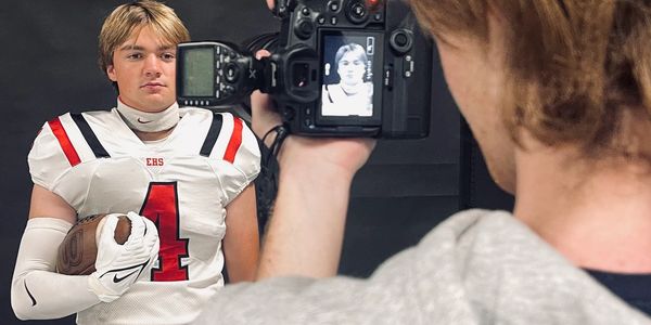 Young football player posing for a portrait photo with a camera.