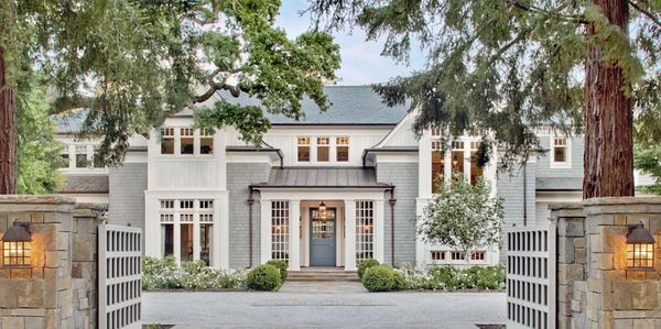 Beautiful traditional home painted in greys and blues with gate opening towards the front door