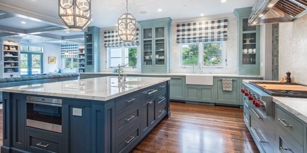 kitchen with dark wood floors and teal green cabinets and dark blue middle isalnd with deco lights