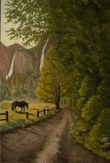 A peaceful rural trail with a horse near a fence and mountains.
