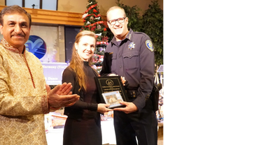 Woman receives an award from a police officer at a festive event.