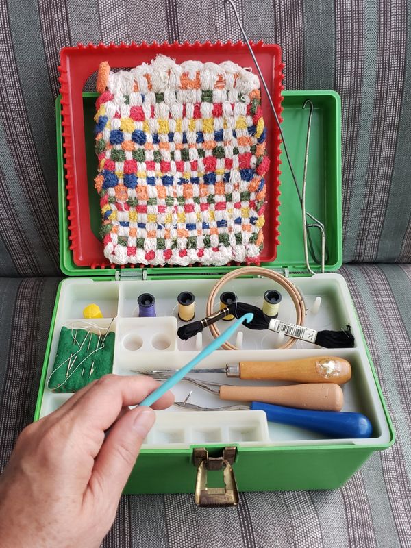 A vintage sewing kit with tools and a handmade woven pouch.