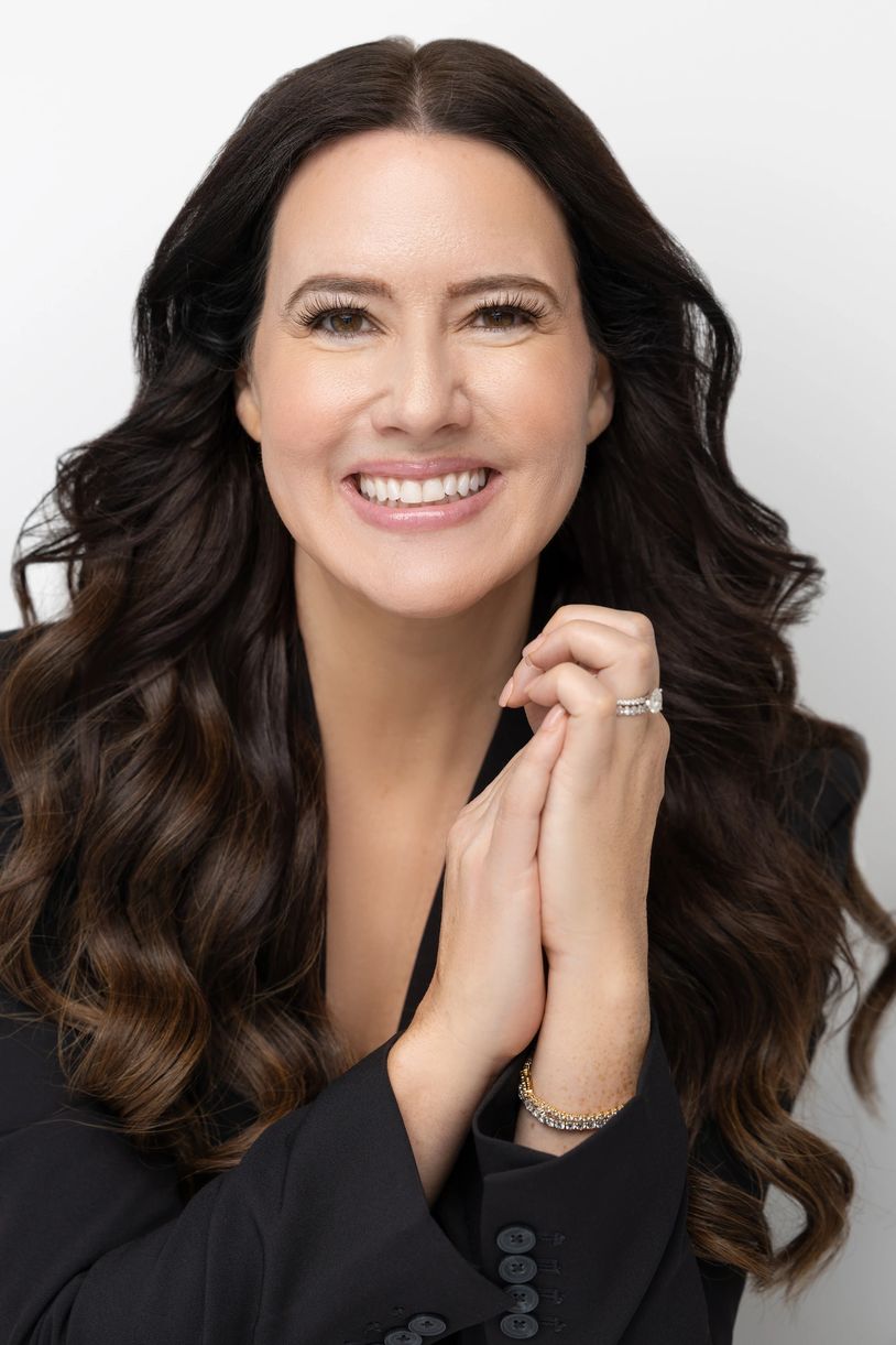 Smiling woman with long wavy hair and elegant jewelry.