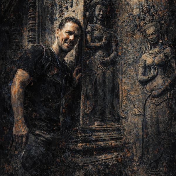 A man smiles beside ancient stone statues in a dimly lit temple.