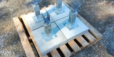 Concrete bases with metal posts on a wooden pallet outdoors.