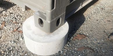 Corner of a container supported by a concrete block on gravel.