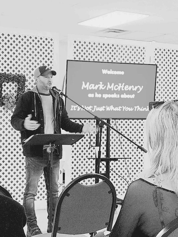 Mark McHenry speaking at a presentation with an audience.