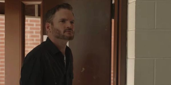 Man standing at a doorway looking thoughtfully.