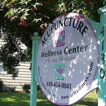 Outdoor sign for acupuncture and wellness center with contact info.