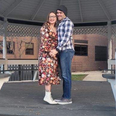 A happy couple embraces under a gazebo on a sunny day.